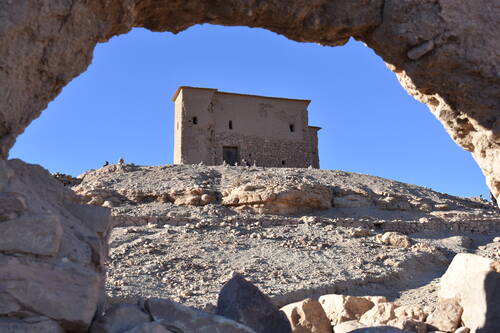 Aït Benhaddou: Looking through a hole in the wall at an old building atop the hill